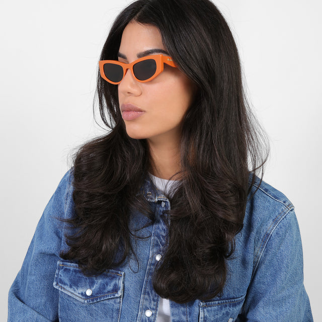 Brunette model in denim looking right wearing Alexa Sunglasses Aperol with Grey Flat