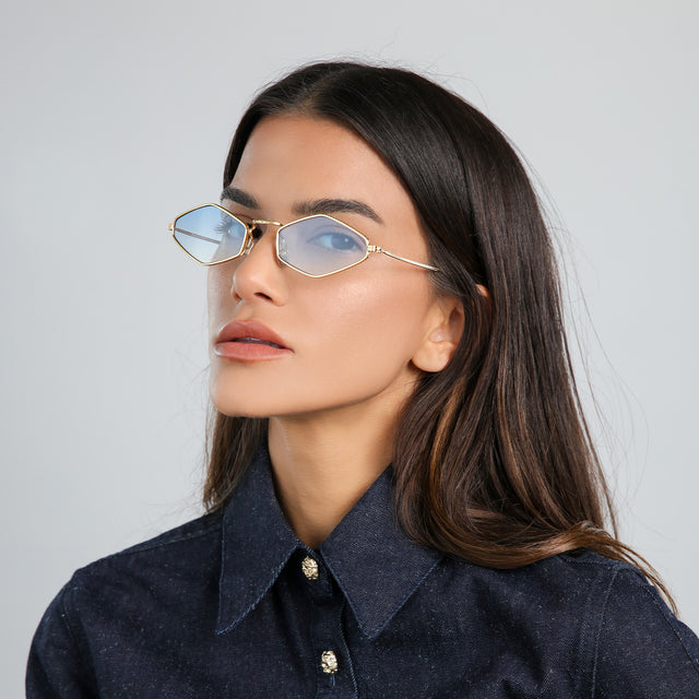 Another angle of woman in a dark blue denim jacket wearing Astoria Sunglasses Gold with Blue Flat Gradient See Through