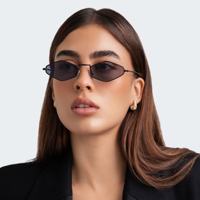A woman in a black blazer wearing Astoria Sunglasses Matte Black with Grey Flat