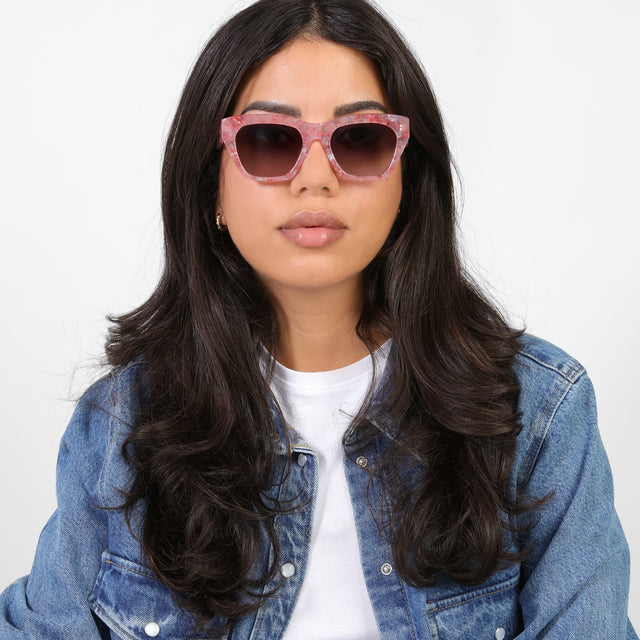 Brunette model in a denim jacket wearing Bali Sunglasses Rose Quartz with Grey Gradient