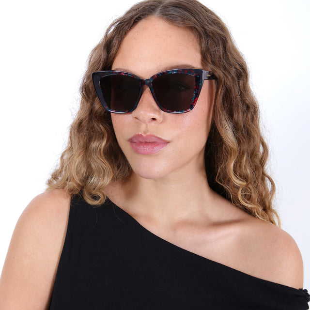 Brunette model with ombré, wavy hair wearing Barcelona Sunglasses Cosmic with Grey Flat