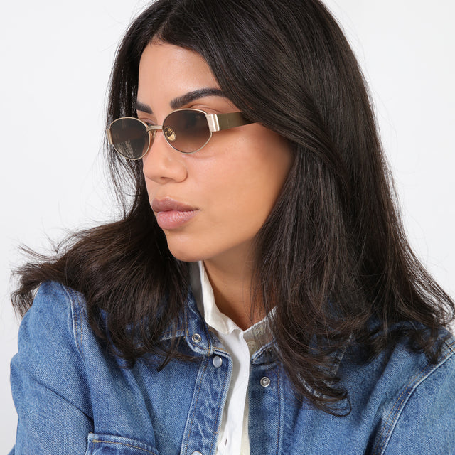 Brunette model in a denim jacket looking right wearing Bellagio Sunglasses Brushed Rose Gold with Taupe Gradient