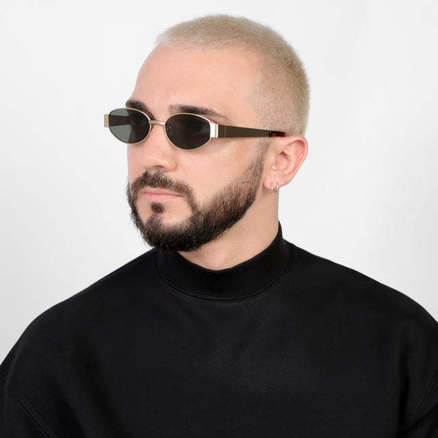 Bearded model in a black mockneck looking right wearing Bellagio Sunglasses Brushed Gold with Grey