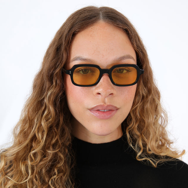 Brunette model with ombré, wavy hair wearing Berlin Sunglasses Black with Honey See Through