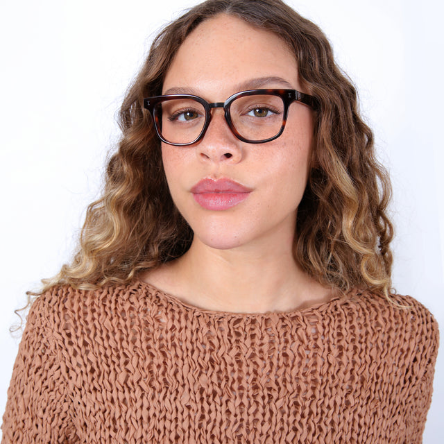 Brunette model with ombré, curled hair wearing Bobby Optical Havana/Matte Black Optical