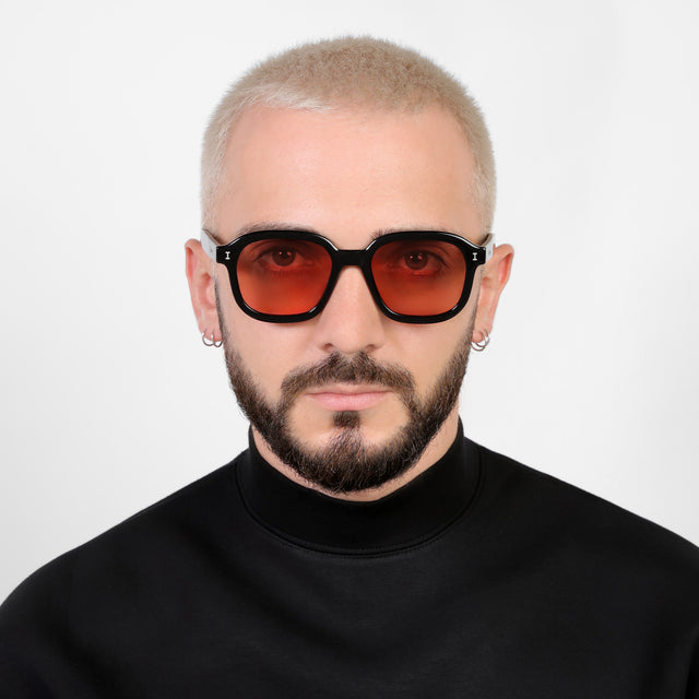 Model with a platinum buzzcut wearing Bogota E Sunglasses Black with Guava See Through