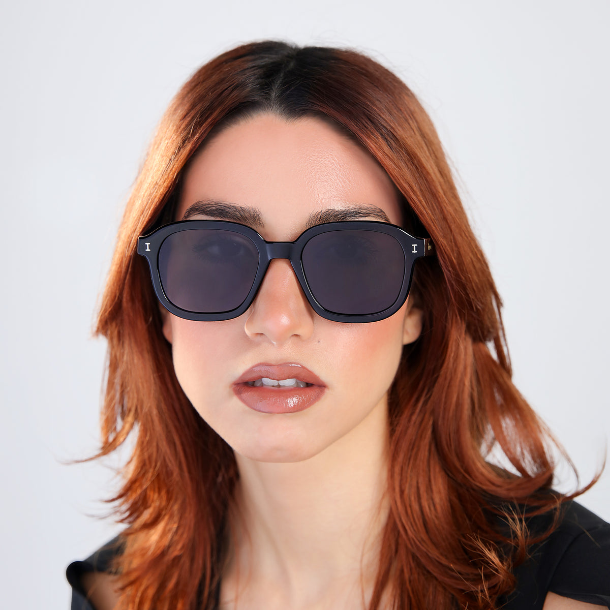 Woman wearing Bogota E Sunglasses in Black with Grey Flat lenses, front view, Woman with red hair in a black blouse