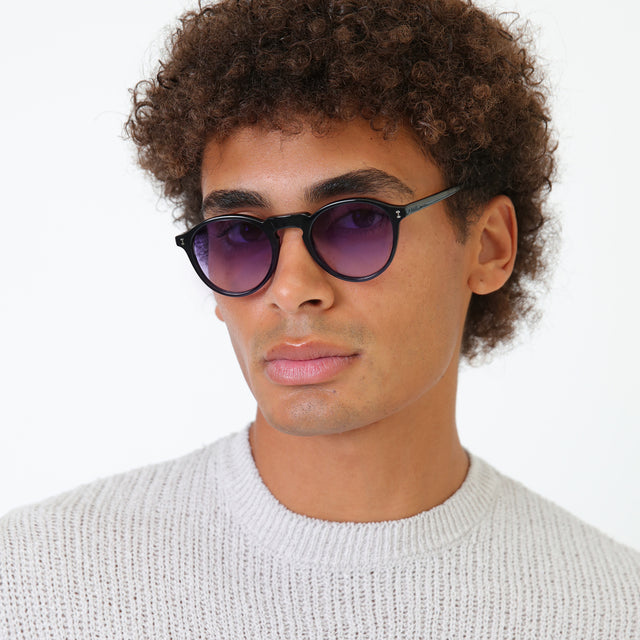 Model with afro-curly hair wearing Capri Sunglasses Black with Purple Gradient