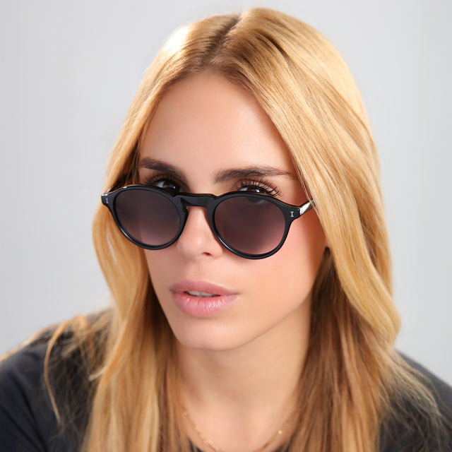 Another angle of blond woman in black tee wearing Capri Sunglasses Black with Grey Gradient