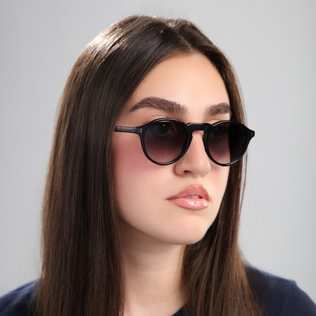 Brunette woman in a navy blouse looking left wearing Capri Sunglasses Black with Grey Gradient