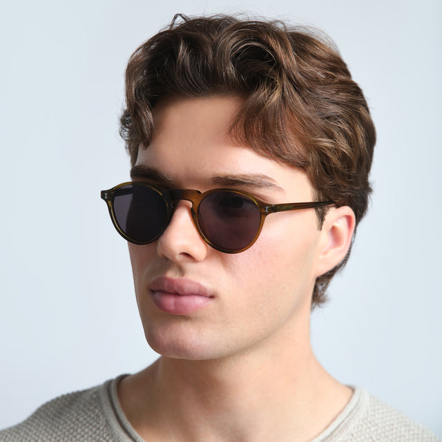 Man in a beige sweatshirt wearing Capri Sunglasses Moss with Grey