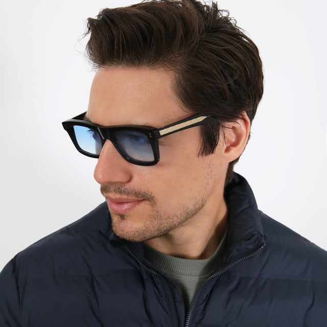 Model with short brown hair turning to his right wearing Catania Sunglasses Black/Gold with Blue Flat Gradient See Through