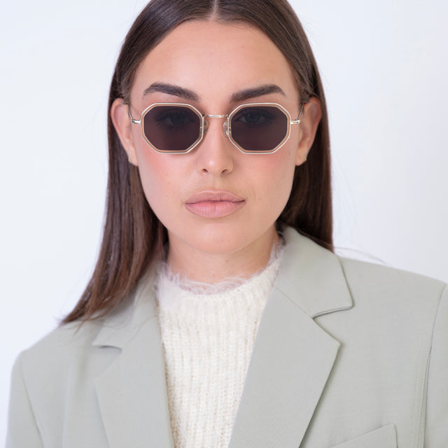 Brunette model with straight hair in a blazer wearing Dylan Tate Sunglasses Citrine Gold with Grey Flat