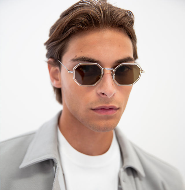 Model with short brown hair combed back wearing Dylan Tate Sunglasses Champagne Silver with Brown Flat Lenses