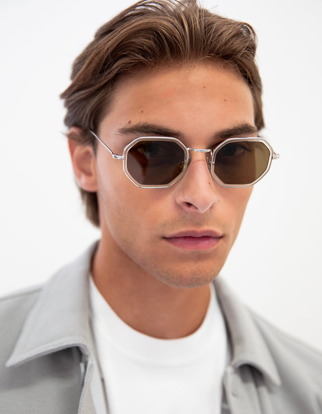 Man with light brown hair combed back wearing the Dylan Sunglasses in Silver / Champagne with Brown lenses.
