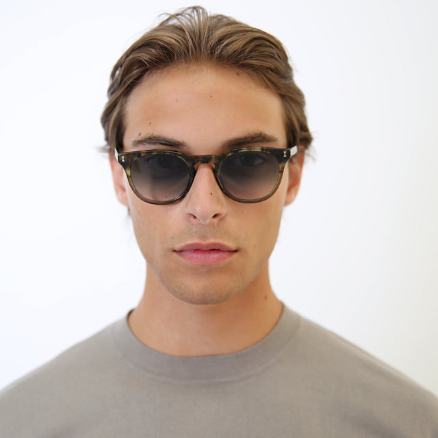 Model with light brown hair combed back wearing Eldridge 48 Light Sunglasses Kale with Grey Flat Gradient