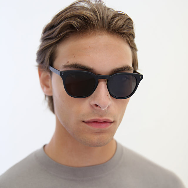 Model with light brown hair combed back wearing Eldridge 48 Light Sunglasses Matte Black with Grey Flat