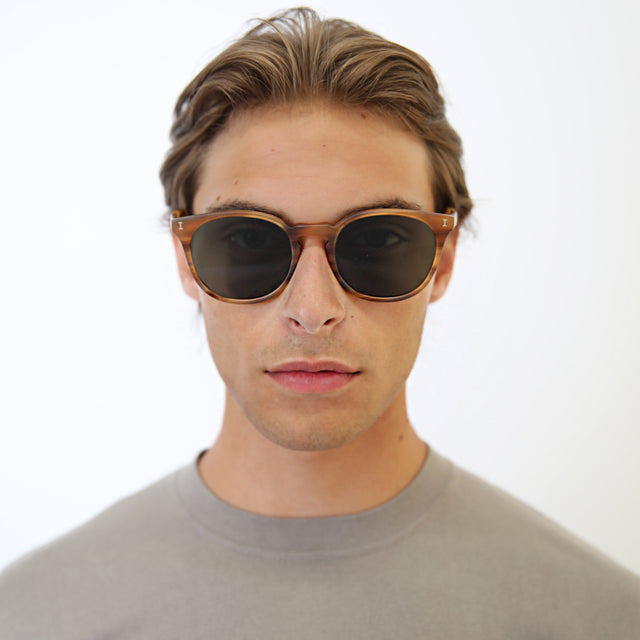 Model with light brown hair combed back wearing Eldridge 56 Light Sunglasses Matte Teak with Olive Flat