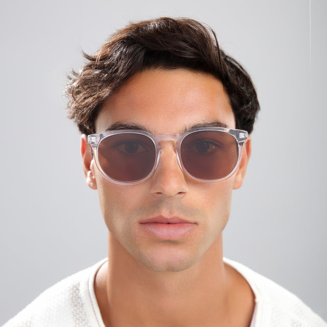 Man with brown hair in a white tee wearing Eldridge 56 Sunglasses Champagne with Brown Flat