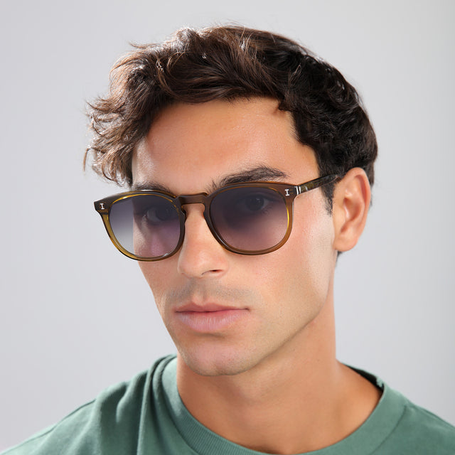 Man with brown hair in a green tee wearing Eldridge 56 Sunglasses Moss with Grey Flat Gradient