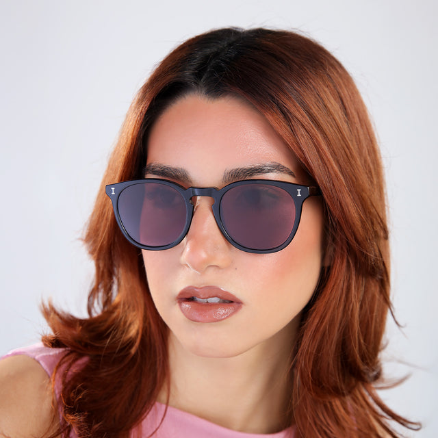 Women with red hair in a pink blouse wearing Eldridge Sunglasses Black with Plum Flat See Through