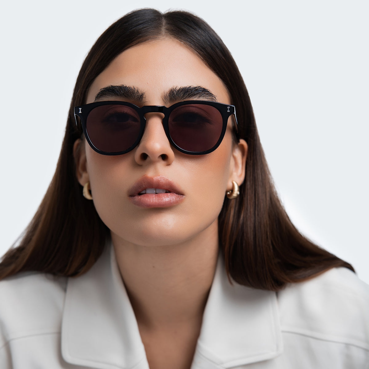 Woman wearing Eldridge Sunglasses in Black with Plum Flat See Through lenses, front view, Woman in a white blazer
