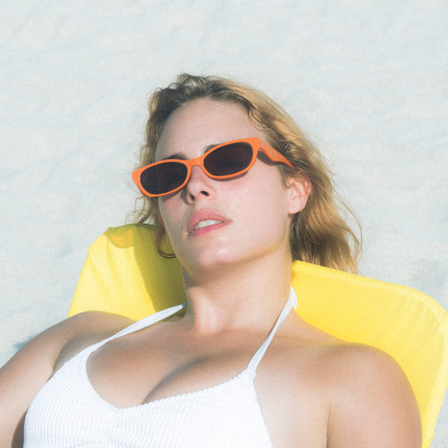 Woman at the beach lounging wearing Encinitas Sunglasses Aperol with Brown