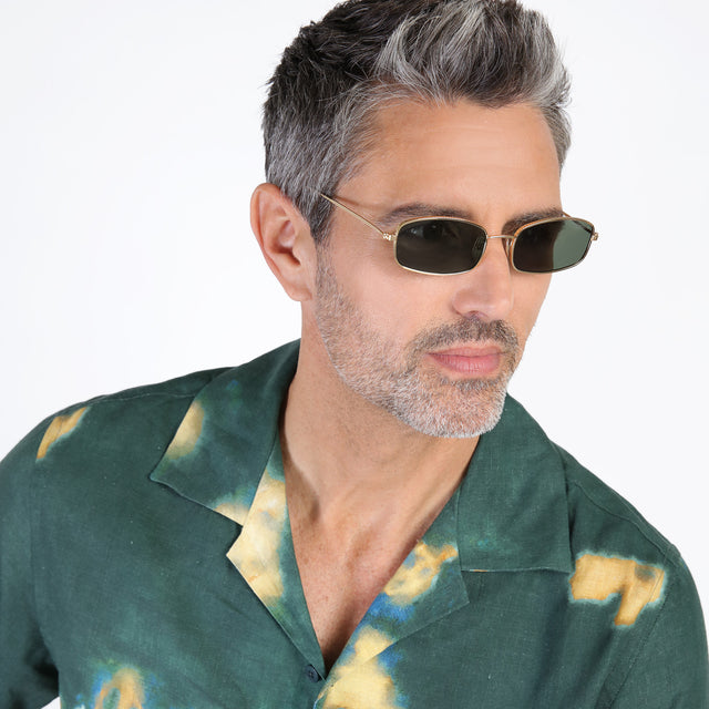 Model with salt and pepper beard looking left wearing Flushing Sunglasses Gold with Olive Flat