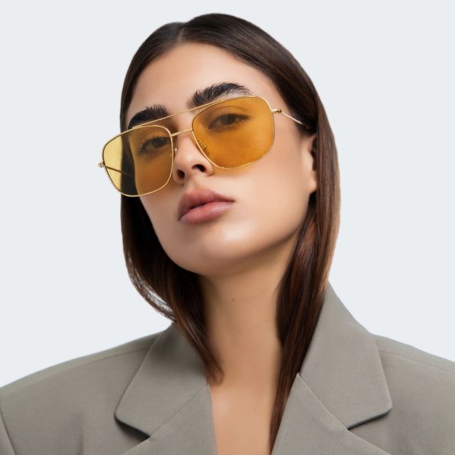Woman in a blazer wearing Frankie Sunglasses Gold with Honey Flat See Through