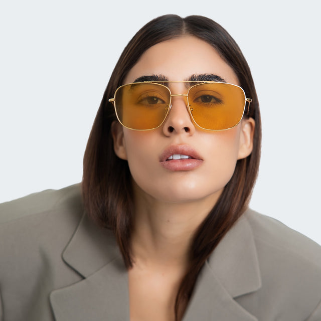 Another angle of woman in a blazer wearing Frankie Sunglasses Gold with Honey Flat See Through