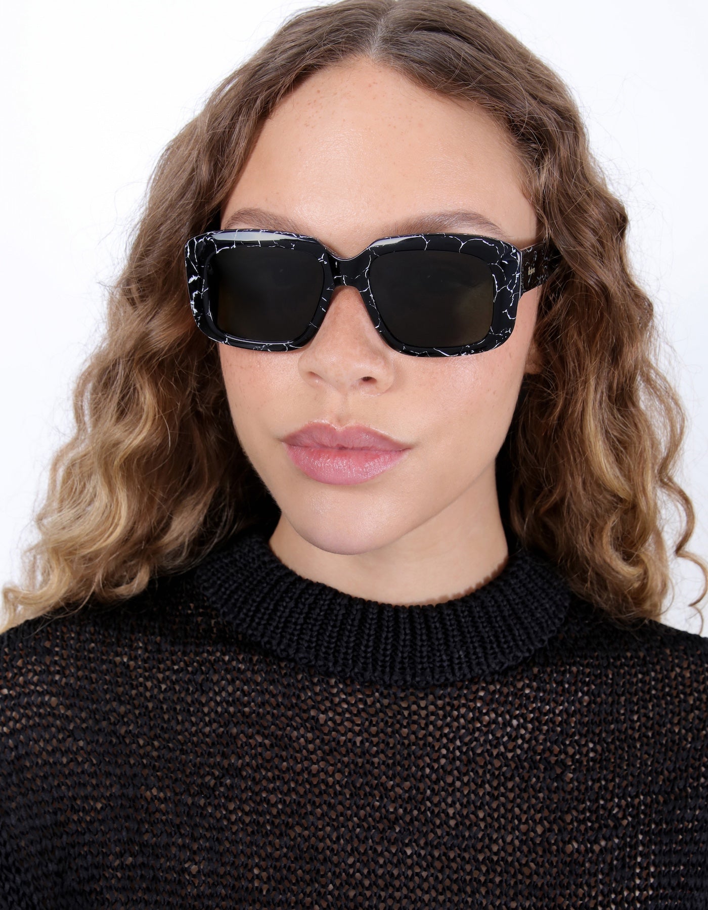 Brunette model with ombré, natural curls wearing Geno Sunglasses in Obsidian with Olive 