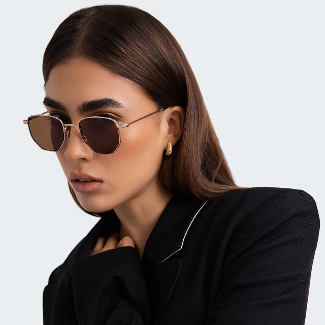 Another angle of woman in a black blazer wearing Hunter Sunglasses Gold with Brown