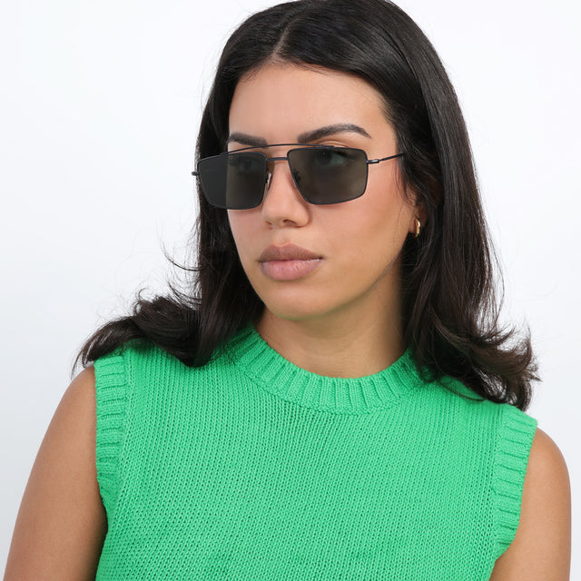 Brunette model with loose curls looking right wearing Jane Sunglasses Matte Black with Olive