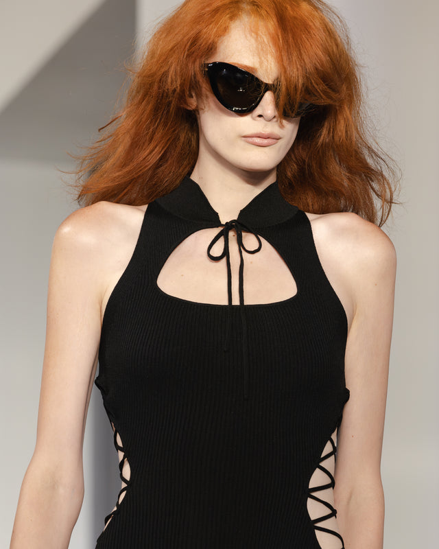 Model wearing a black halter top with cut-out sides and the Kim Shui x illesteva sunglasses in Black