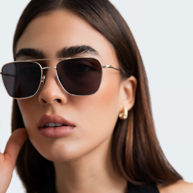 Close up of woman with gold hoop earrings wearing Lafayette Sunglasses Gold with Grey Flat