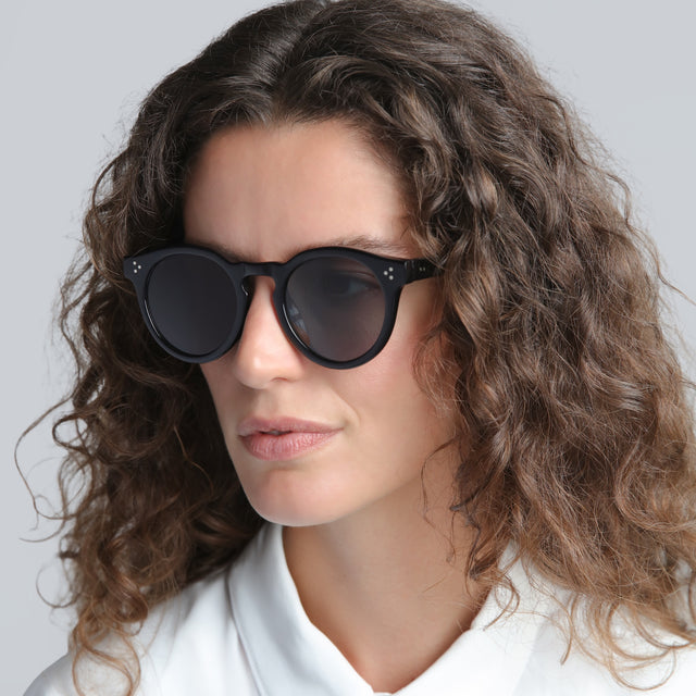 Brunette woman with curls wearing Leonard II E Sunglasses Black with Grey