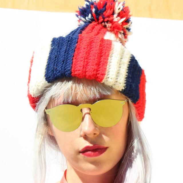 Model in a red, white, and blue striped yarn beanie wearing Leonard Mask Sunglasses Gold with Gold