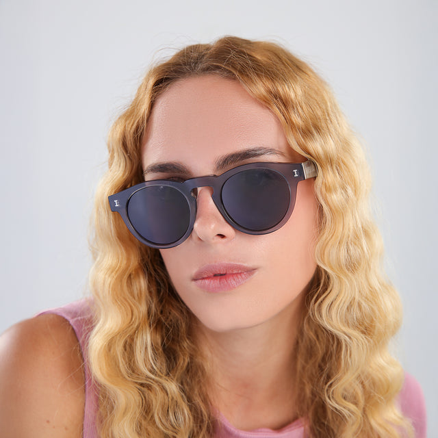 Blonde woman in a bubblegum pink blouse wearing Leonard Sunglasses Mercury with Grey