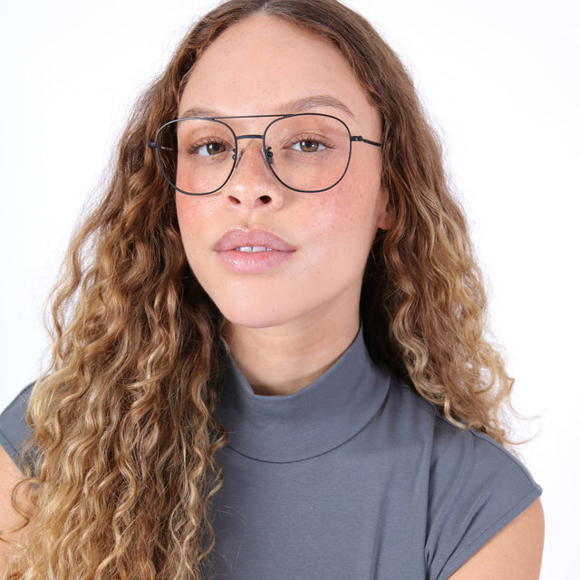 Brunette model with ombre, natural curls wearing Limassol Optical Matte Black Optical