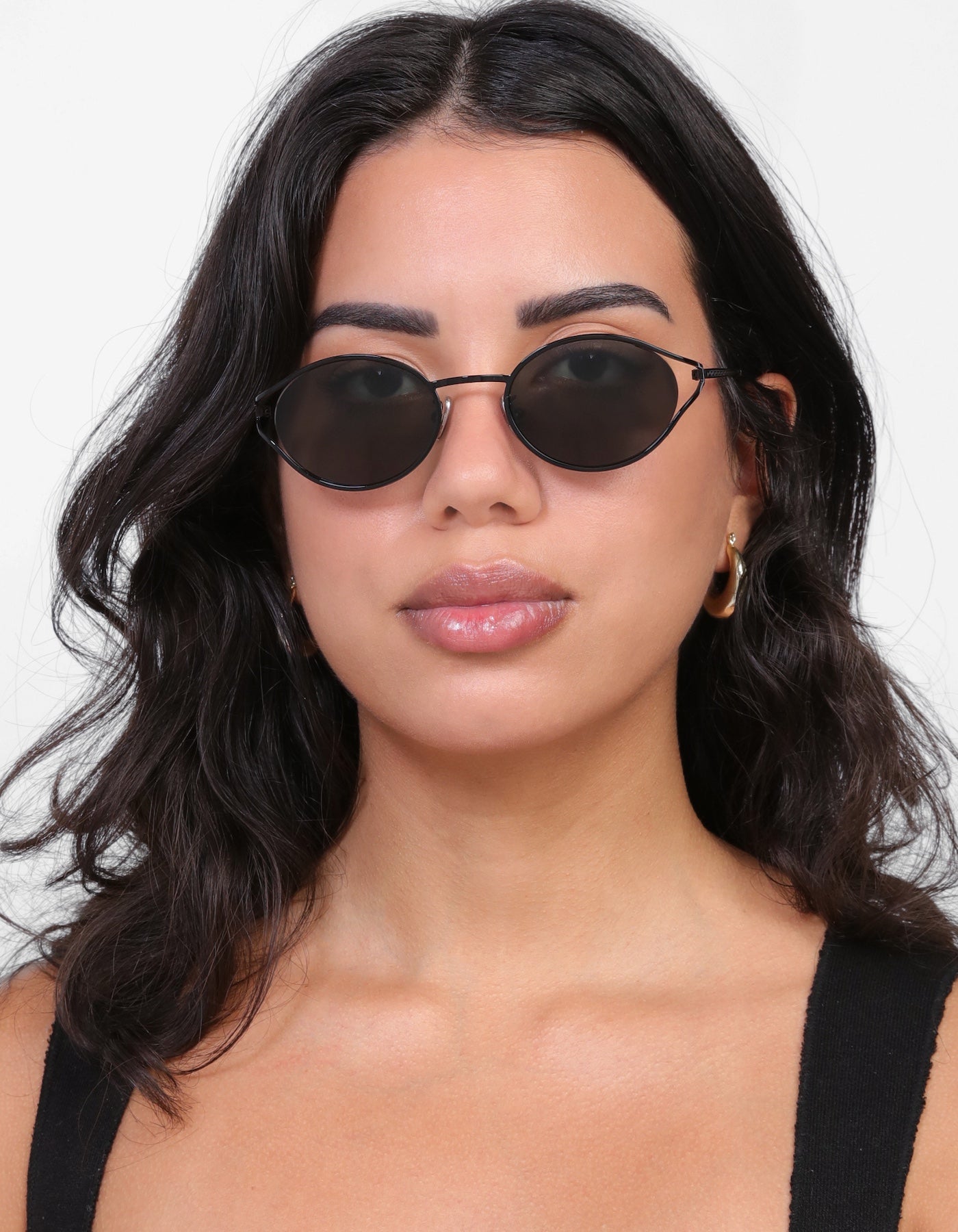 Brunette model with loose curls wearing Maria Sunglasses in Black