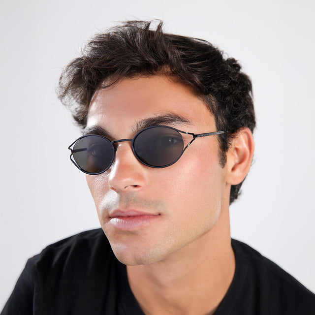 Man with brown hair in a black shirt wearing Maria Sunglasses Black with Grey