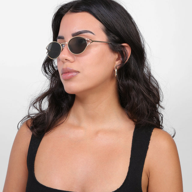 Brunette model looking right wearing Maria Sunglasses Gold with Grey