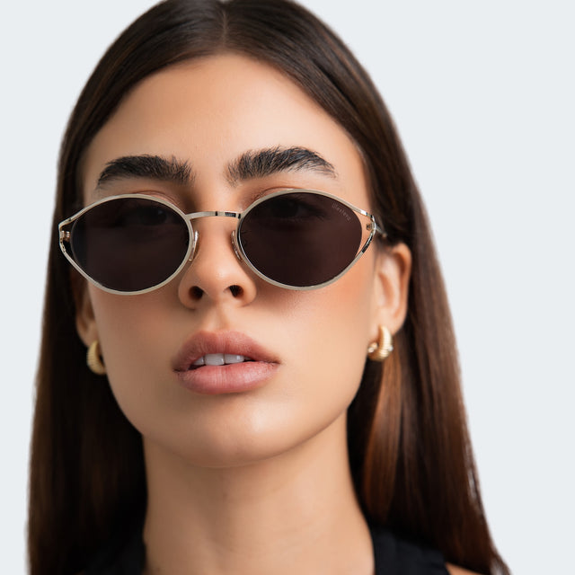 Woman in a black halter blouse wearing Maria Sunglasses Gold with Grey
