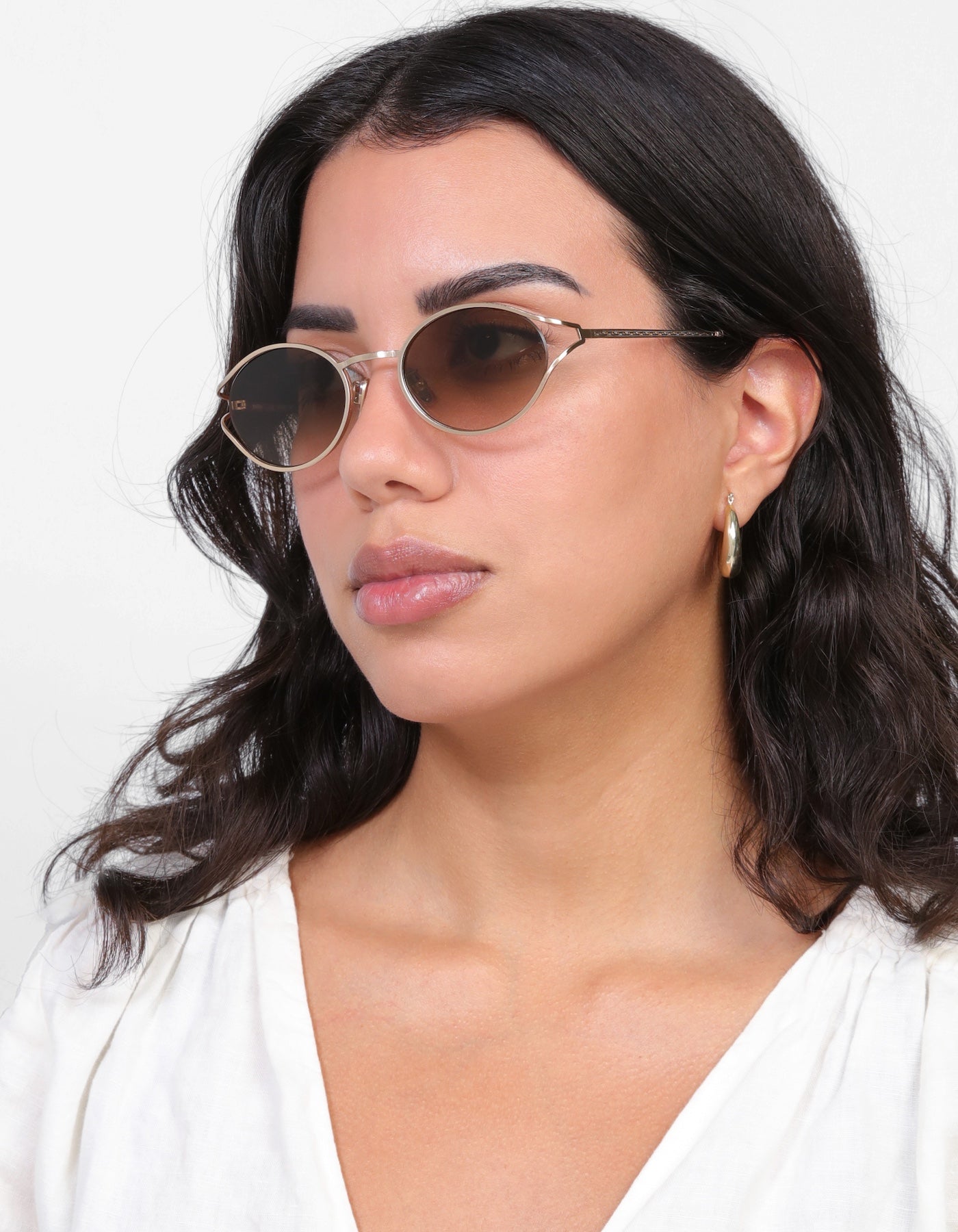 Brunette model with loose curls wearing Maria Sunglasses in Rose Gold