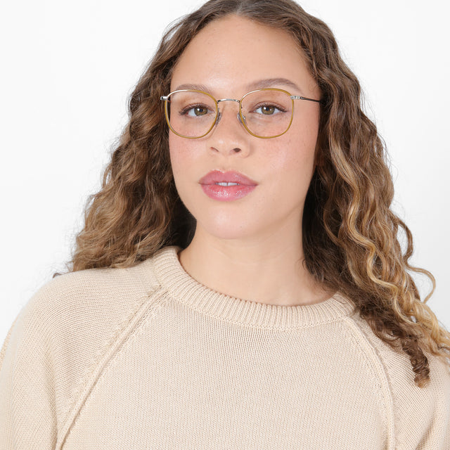 Brunette model with ombré, natural curls wearing Mayfair Optical Saddle/Silver Optical