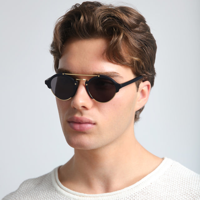 Man in a waffled sweatshirt wearing Milan Sunglasses Matte Black/Gold with Grey