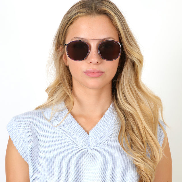 Blonde model with wavy hair wearing Mykonos Ace Sunglasses Iris/Black with Grey Flat