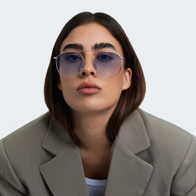 Another angle of woman in an oversized gray blazer wearing Mykonos M Sunglasses Gold with Blue Flat Gradient See Through