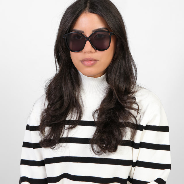 Brunette model in a black and white turtleneck wearing Nancy 57 Sunglasses Black with Grey