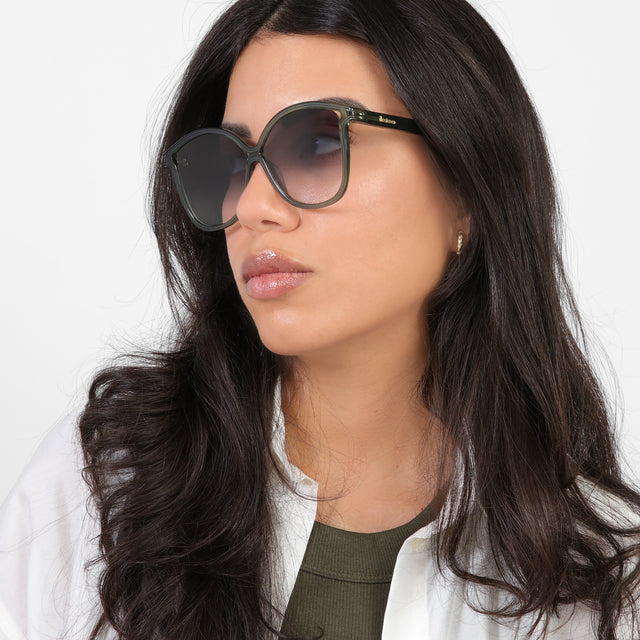 Brunette model in a white blouse looking right wearing Nancy 57 Sunglasses Pine with Grey Gradient